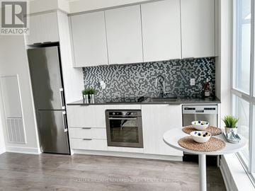 Toronto (Flemingdon Park) condo for rent - A modern kitchen with white cabinets and a black and white backsplash.