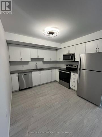 Kitchener condo for rent - A modern kitchen with stainless steel appliances and white cabinets.