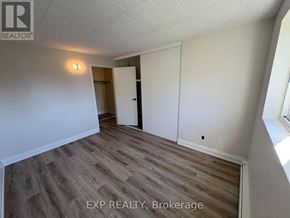 Niagara Falls (Downtown) apartment for rent - A room with wooden flooring and white walls, with a door on the left and a window on the right.