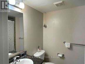 Ottawa townhouse for rent - A bathroom with a toilet, sink, and mirror.