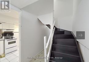Vaughan (Lakeview Estates) apartment for rent - A staircase in a house with a white wall and a doorway leading to a kitchen.