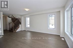Haldimand townhouse for rent - A spacious room with a staircase on the left and a window on the right.