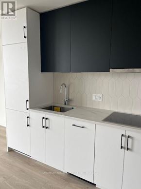 Kitchener condo for rent - A kitchen with white cabinets and a black backsplash.