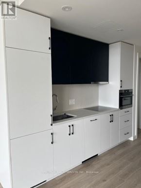 Kitchener condo for rent - A kitchen with white cabinets and a black countertop.