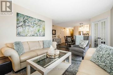 Brampton (Goreway Drive Corridor) condo for rent - A living room with a beige couch, a glass coffee table, and a painting on the wall.