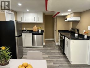 Kitchener apartment for rent - A kitchen with a black refrigerator and white cabinets.