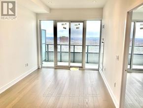 Toronto (Mimico) condo for rent - A spacious room with wooden floors and sliding glass doors leading to a balcony.