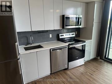 Brantford condo for rent - A modern kitchen with white cabinets and stainless steel appliances.