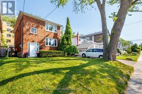 Toronto (Birchcliffe-Cliffside) triplex for rent - A red brick house with a white garage door and a tree in front.