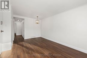 Toronto (Birchcliffe-Cliffside) triplex for rent - A room with wooden floors and white walls, with a door on the left and a light hanging from the ceiling.