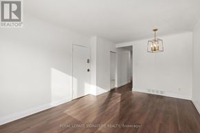Toronto (Birchcliffe-Cliffside) triplex for rent - A room with wooden floors and white walls, with a chandelier hanging from the ceiling.