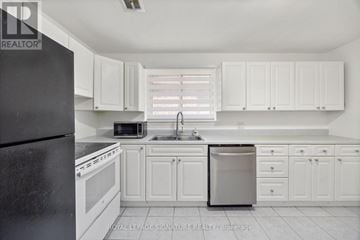 Toronto (Birchcliffe-Cliffside) triplex for rent - A kitchen with white cabinets and a black refrigerator.