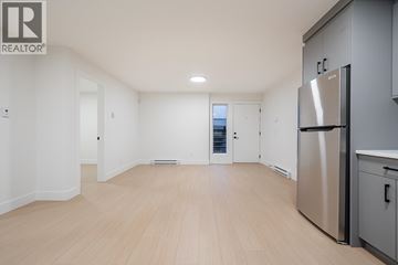 Burnaby apartment for rent - A spacious kitchen with a refrigerator and wooden flooring.