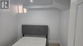 Haldimand apartment for rent - A bed with a grey headboard in a white room.