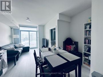 Toronto (York University Heights) condo for rent - A dining room with a table set for two and a living room with a couch and television in the background.