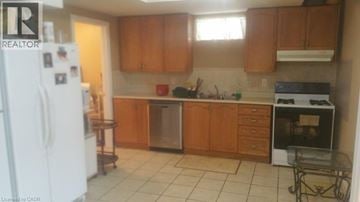 Ancaster apartment for rent - A kitchen with a white fridge, wooden cabinets, and a black stove top oven.
