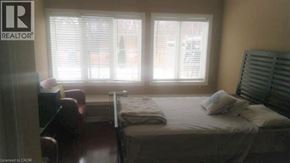 Ancaster apartment for rent - A bedroom with a bed, a chair, and a window with blinds.