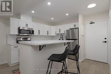 St. Marys condo for rent - A kitchen with white cabinets and a countertop with two black chairs.