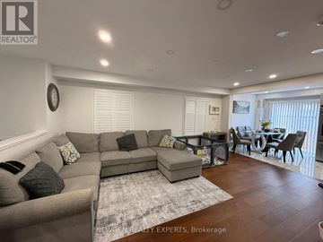 Toronto (Flemingdon Park) apartment for rent - A spacious living room with a grey sofa set and a dining table with chairs.