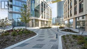 Vaughan (Vaughan Corporate Centre) condo for rent - A modern courtyard with a stone pathway and a grassy area with a tree in the middle.