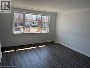 Hamilton apartment for rent - A room with a large window showing a view of a residential area.