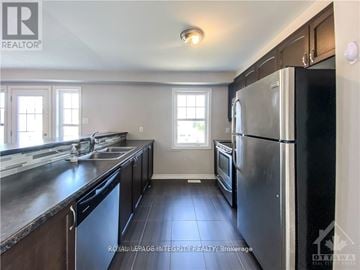 Ottawa townhouse for rent - A kitchen with a black refrigerator and a sink.