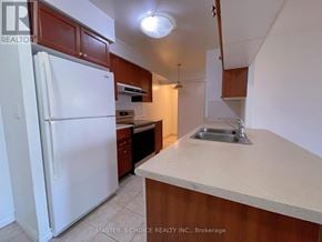 Mississauga (City Centre) condo for rent - A kitchen with a white refrigerator and brown cabinets.