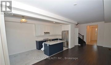 Hamilton (Ancaster) townhouse for rent - A spacious kitchen with white cabinets and a dark island.