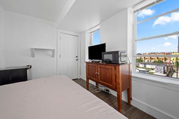 Atlantic City apartment for rent - A bedroom with a bed, a television, and a window overlooking a cityscape.