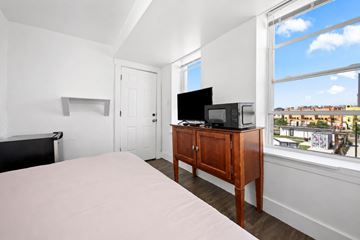 Atlantic City apartment for rent - A bedroom with a bed, a television, and a window overlooking a cityscape.