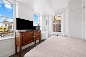 Atlantic City apartment for rent - A bedroom with a large bed, a television, and a window overlooking a city street.