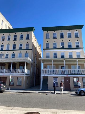 Atlantic City apartment for rent - Two men are standing on the sidewalk in front of a building with a balcony.