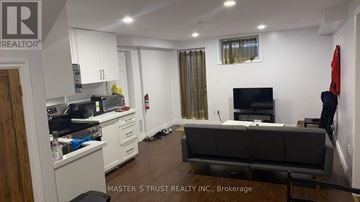 Guelph (Kortright East) apartment for rent - A well-lit, clean living room with a grey couch and a television.