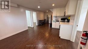 Guelph (Kortright East) apartment for rent - A grey couch is in the foreground of a well-lit kitchen and dining area.