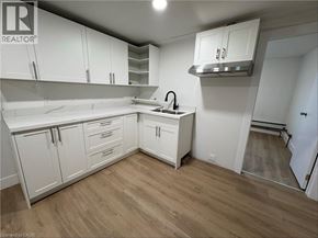 Port Colborne apartment for rent - A kitchen with white cabinets and a wooden floor.