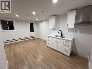Port Colborne apartment for rent - A kitchen with white cabinets and a wooden floor.