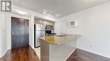 Toronto (Waterfront Communities) condo for rent - A kitchen with a granite countertop and a refrigerator with a stainless steel finish.