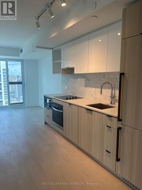 Toronto (Church-Yonge Corridor) condo for rent - A modern kitchen with wooden cabinets and a marble backsplash.