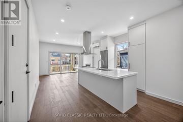 Toronto (The Beaches) apartment for rent - A modern kitchen with a white island and wooden floors.
