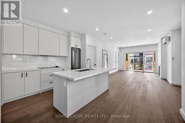 Toronto (The Beaches) duplex for rent - A modern kitchen with white cabinets and a central island.