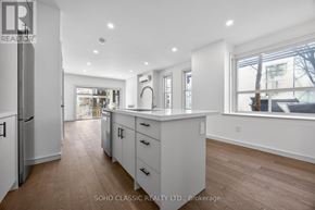 Toronto (The Beaches) duplex for rent - A spacious kitchen with white cabinets and a wooden floor.