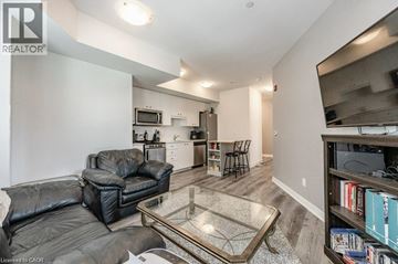 Kitchener condo for rent - A living room with a black leather couch and a glass coffee table.