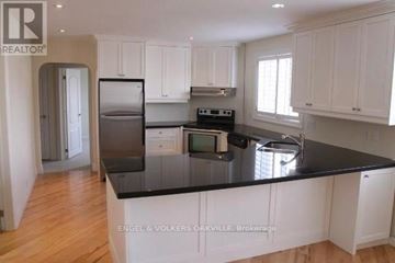 Oakville (Oo Old Oakville) condo for rent - A kitchen with white cabinets and a black countertop.