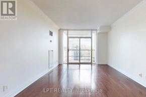 Toronto (Yonge-St. Clair) condo for rent - A room with wooden floors and white walls, with a large window and a view of a cityscape outside.