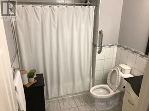 Toronto (Humber Summit) apartment for rent - A white shower curtain in a bathroom with a toilet and a small plant on a shelf.
