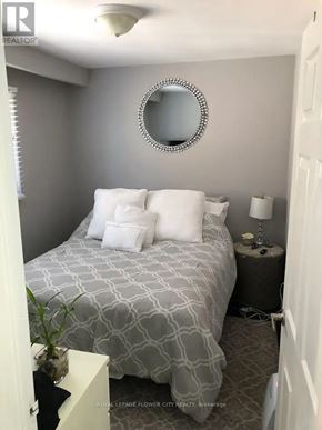 Toronto (Humber Summit) apartment for rent - A bedroom with a bed, nightstand, lamp, and a mirror on the wall.