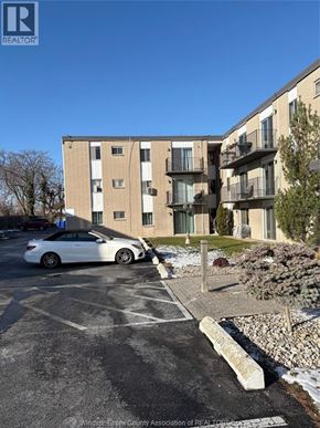 Windsor apartment for rent - A white car is parked in a parking lot in front of a building.