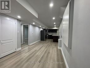 Brampton (Northwest Brampton) apartment for rent - A hallway with wood flooring and white walls, leading to a dark room with a desk.