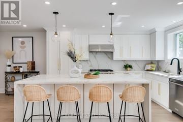Toronto (Stonegate-Queensway) apartment for rent - A modern kitchen with white cabinets and a central island with three chairs.