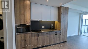 Kitchener condo for rent - A modern kitchen with wooden cabinets and a stainless steel countertop.